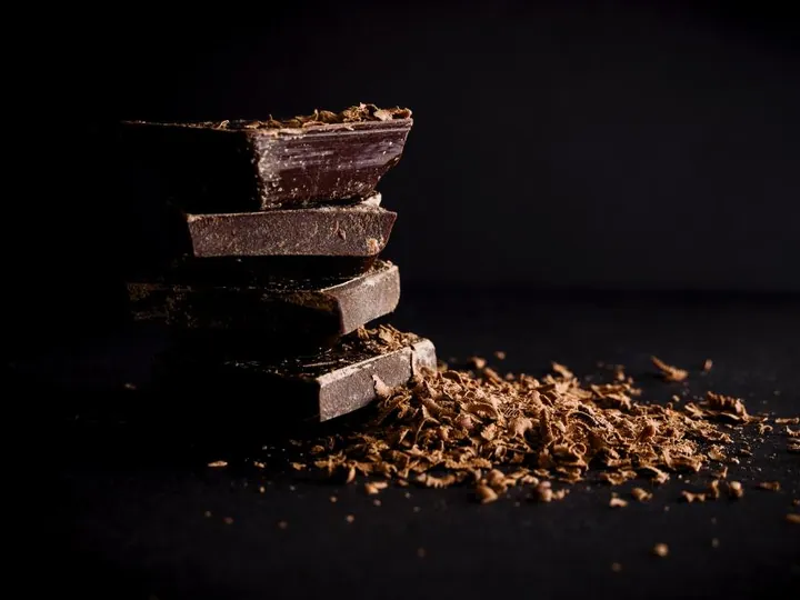 Carrés de chocolat noir empilés et copeaux de chocolat